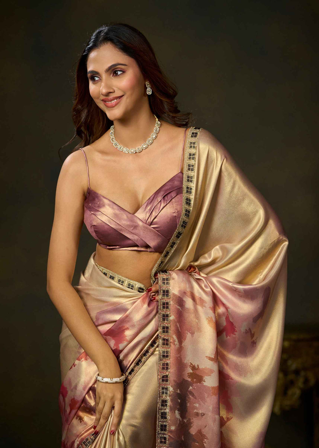 Woman wearing a pink watercolor printed satin silk saree with a matching blouse and elegant draping.