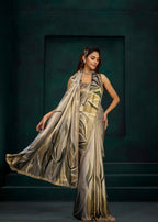 A woman models a metallic gold and silver saree with a matching dupatta against a dark teal studio backdrop.