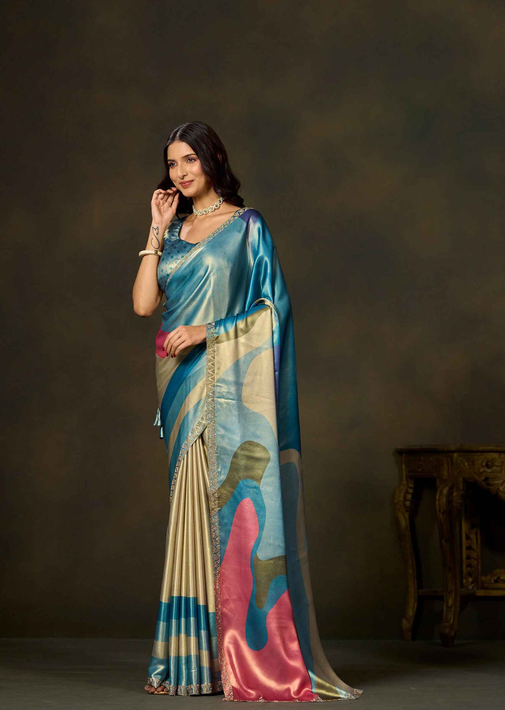 Woman wearing blue satin silk saree with colorful geometric color block prints and embellished border.