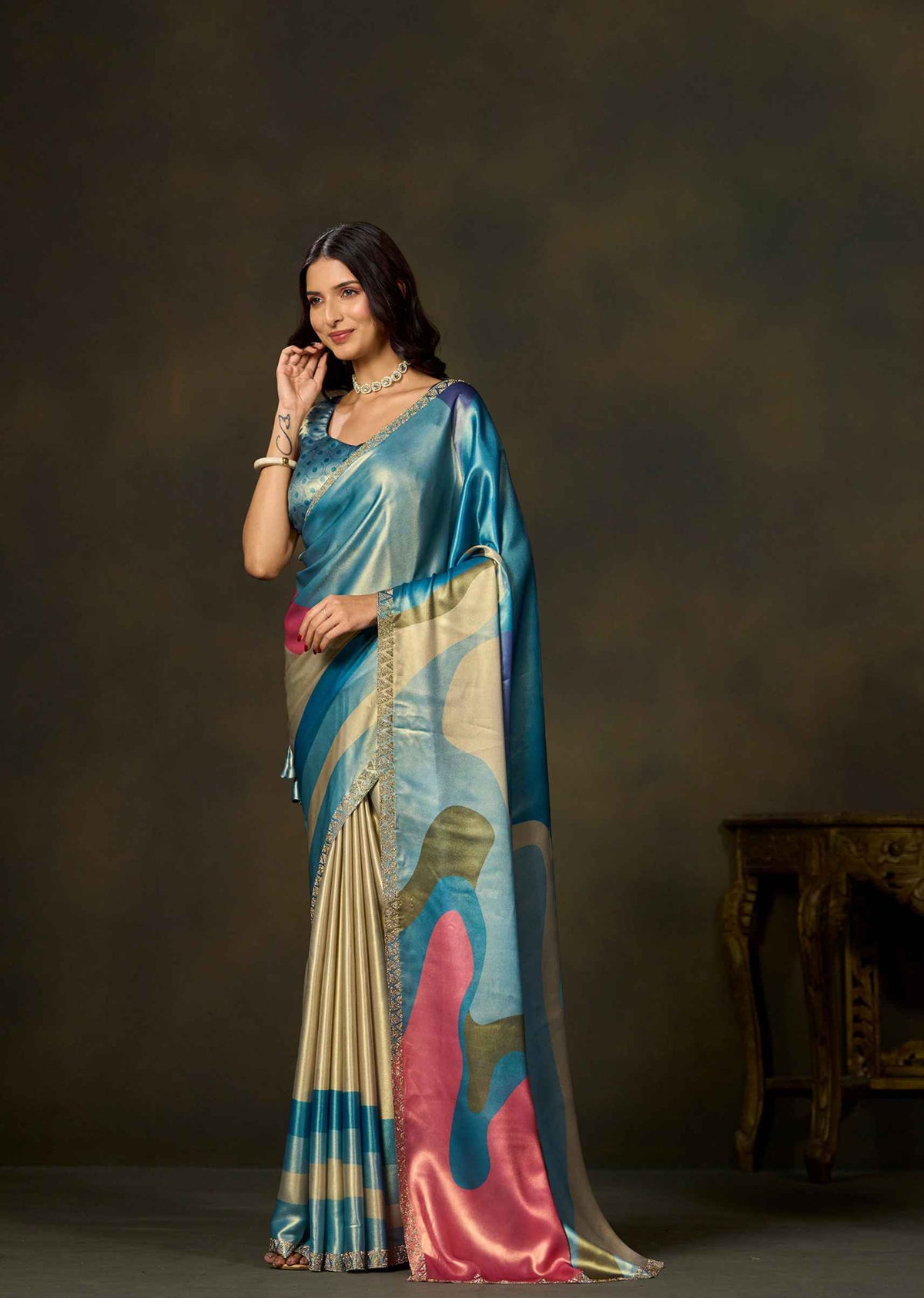 Woman wearing blue satin silk saree with colorful geometric color block prints and embellished border.