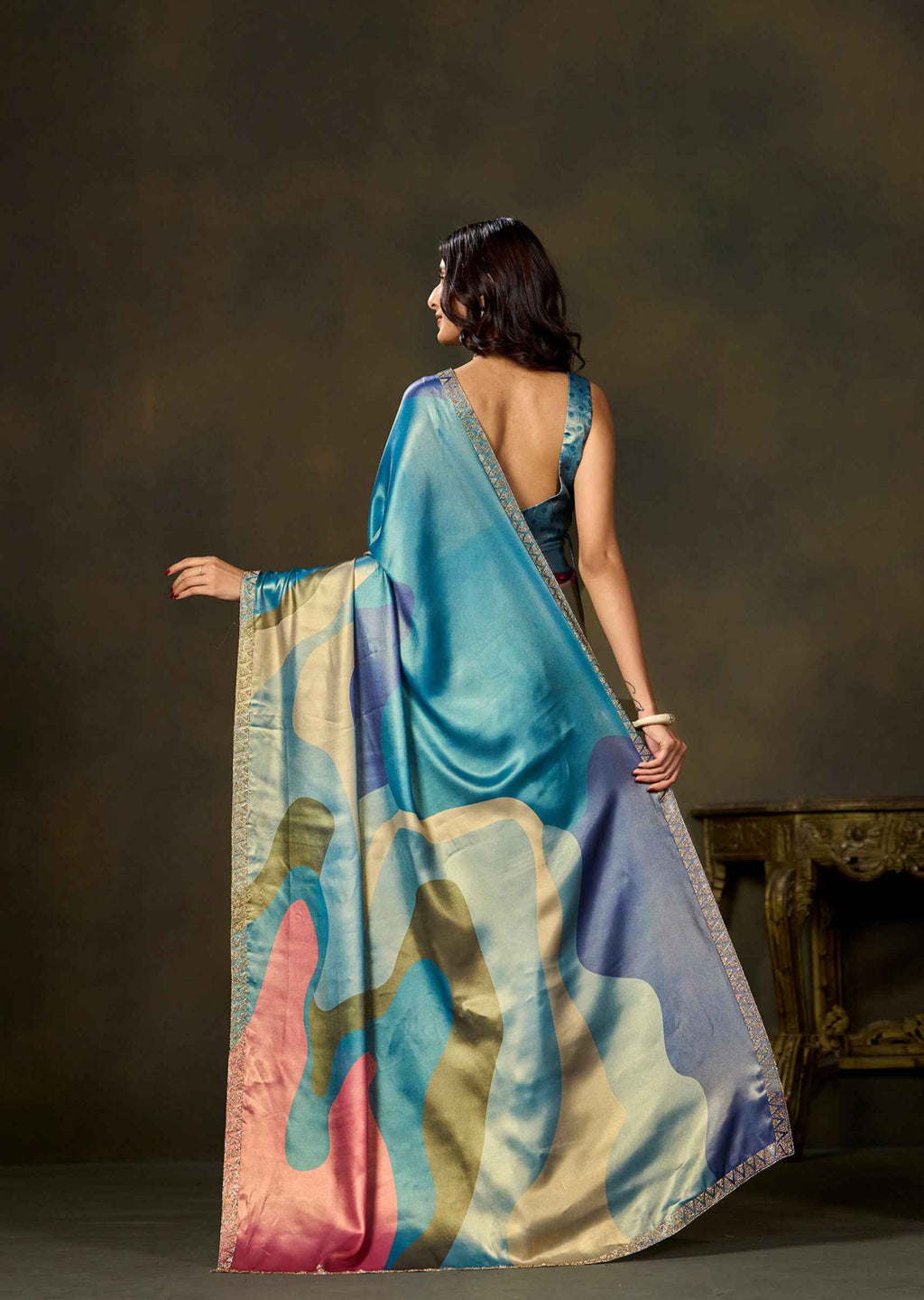 Back view of blue color block printed satin silk saree with flowing pallu and multicolor patterns by Ethnic9.