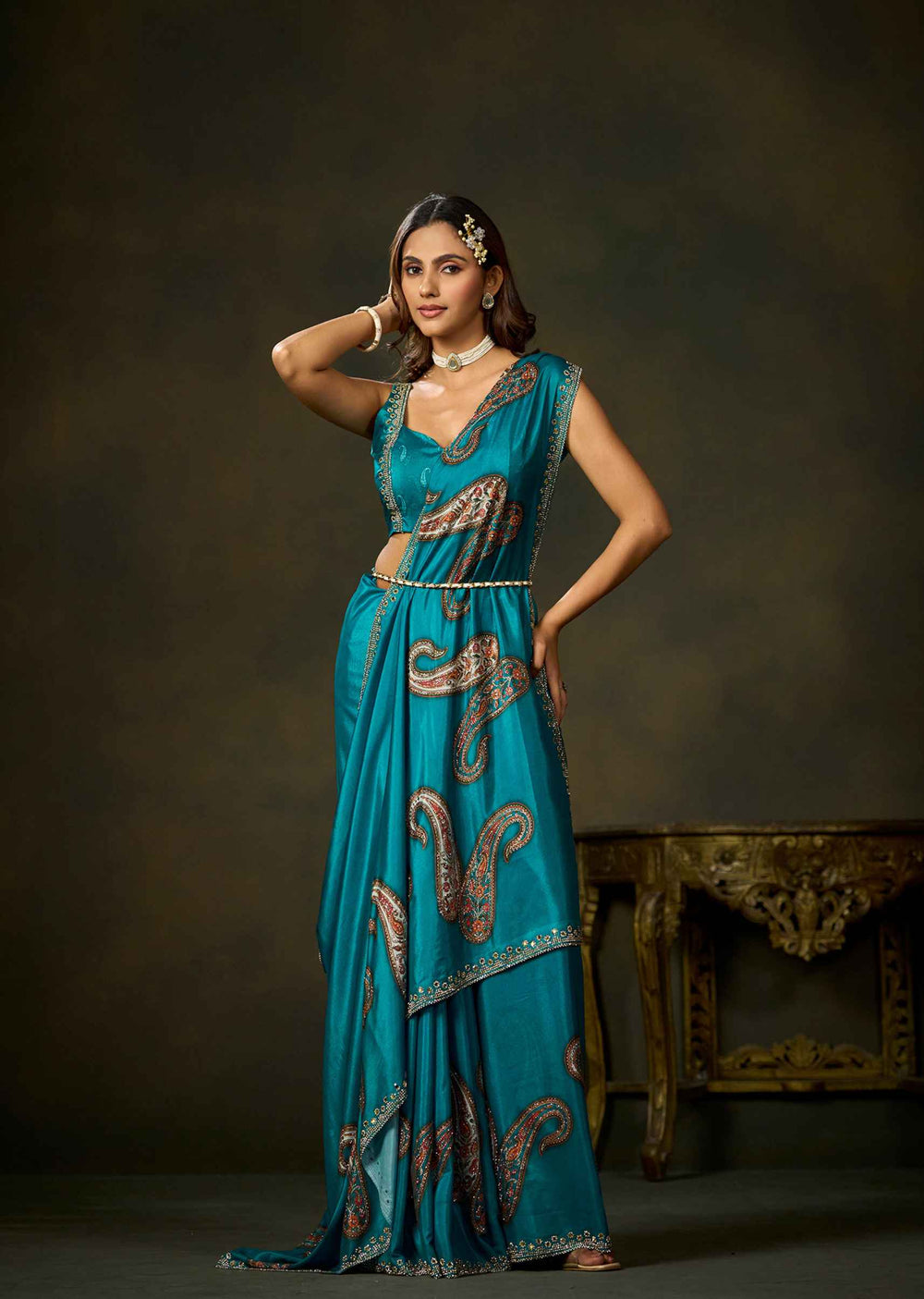 Woman wearing firozi satin silk saree with paisley embellishments and elegant matching blouse.