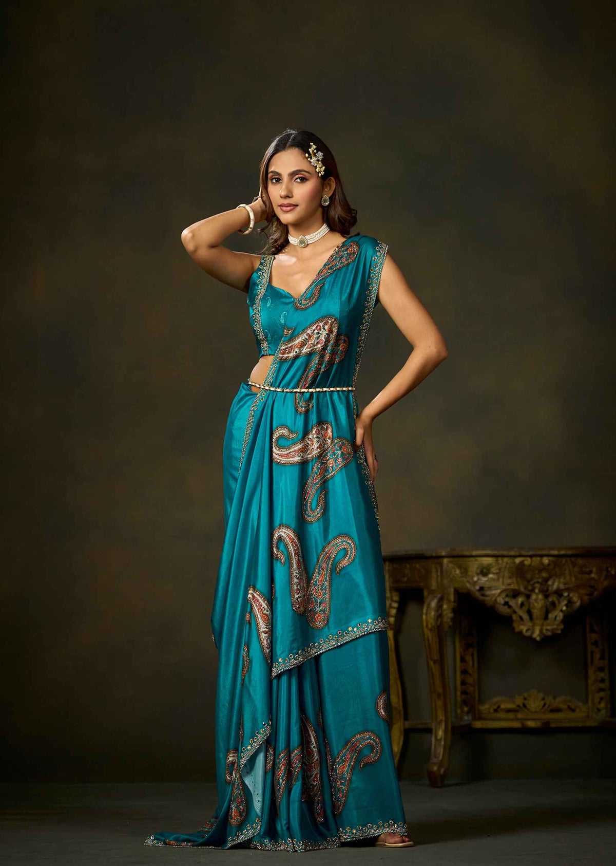 Woman wearing firozi satin silk saree with paisley embellishments and elegant matching blouse.