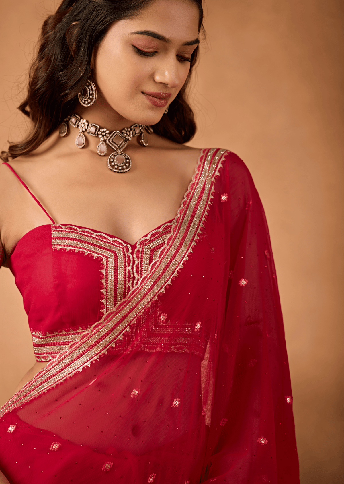 A woman wearing a red saree with gold embroidery and a matching red blouse