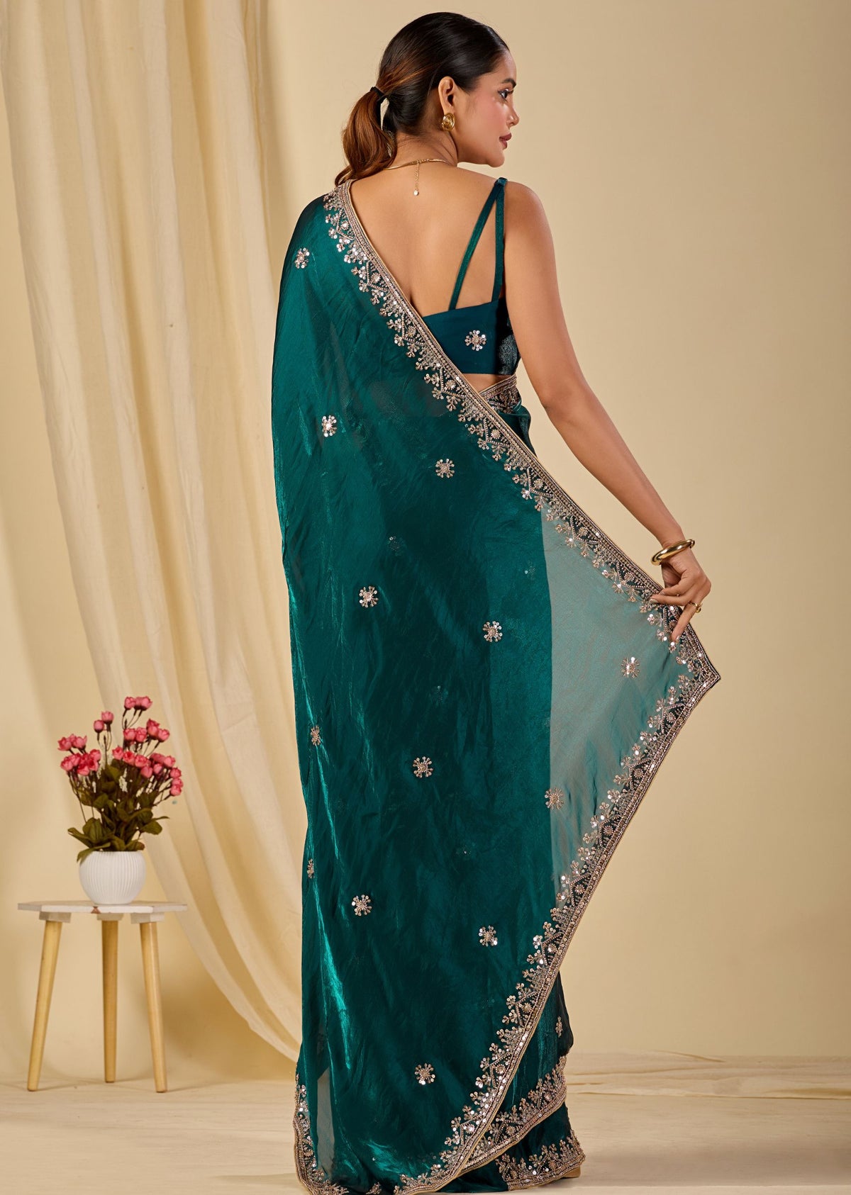 Teal green designer organza saree with shimmering floral motifs