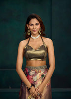 A woman modeling a metallic bronze halter crop top and a floral printed skirt against a dark teal background.