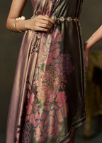 A close-up of a woman wearing a shimmering satin dress with a large pink floral brocade pattern over a dark base, styled with a gold chain belt and pearl bracelets.