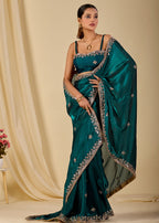 Model wearing teal green sheer organza saree with embroidered border
