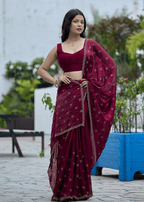 A woman wearing a deep maroon red saree