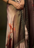 A close-up of a draped satin saree with a brown and beige gradient, featuring a pink floral print and a black-and-white checkered border.