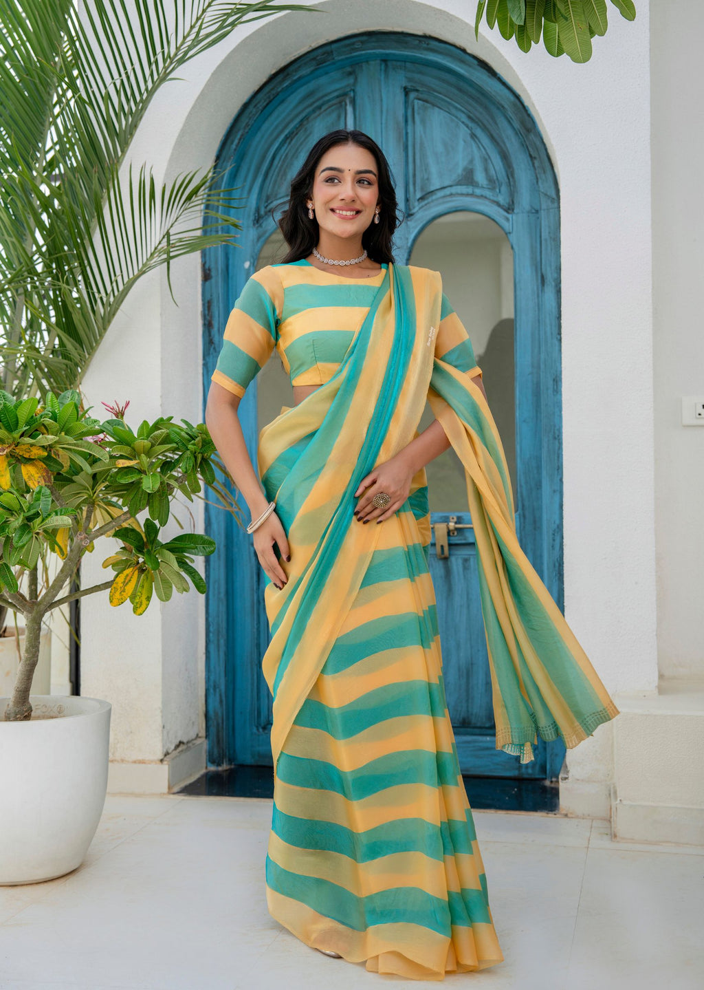A woman wearing a yellow and teal striped saree