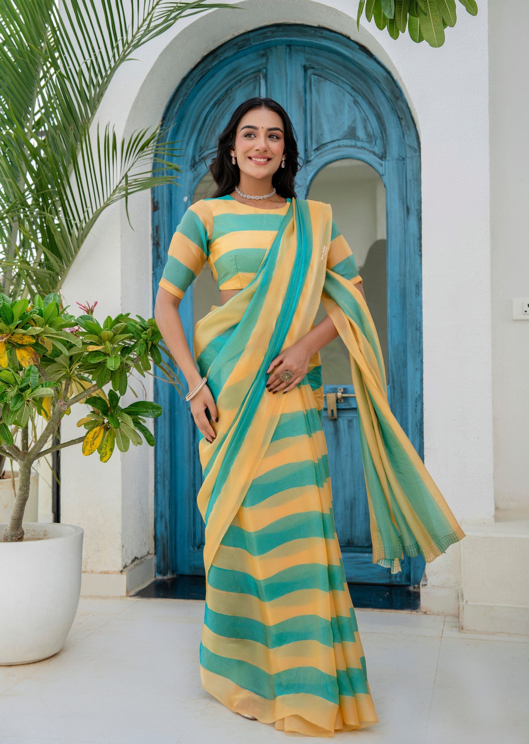 A woman wearing a yellow and teal striped saree