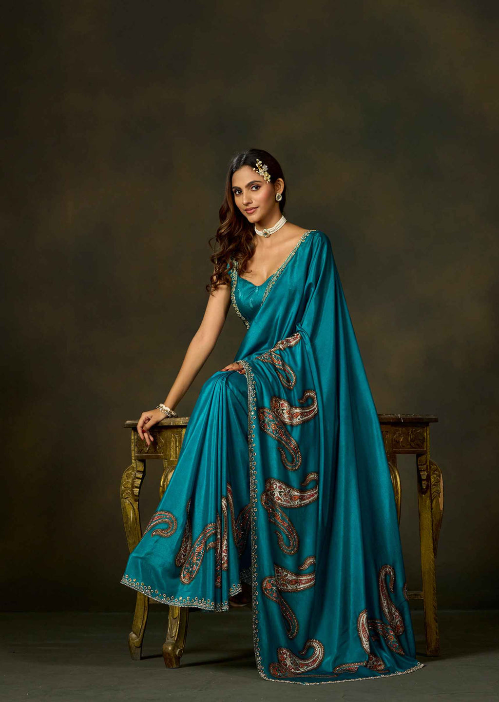Full-length firozi satin silk saree with paisley embellished pallu and elegant traditional draping.